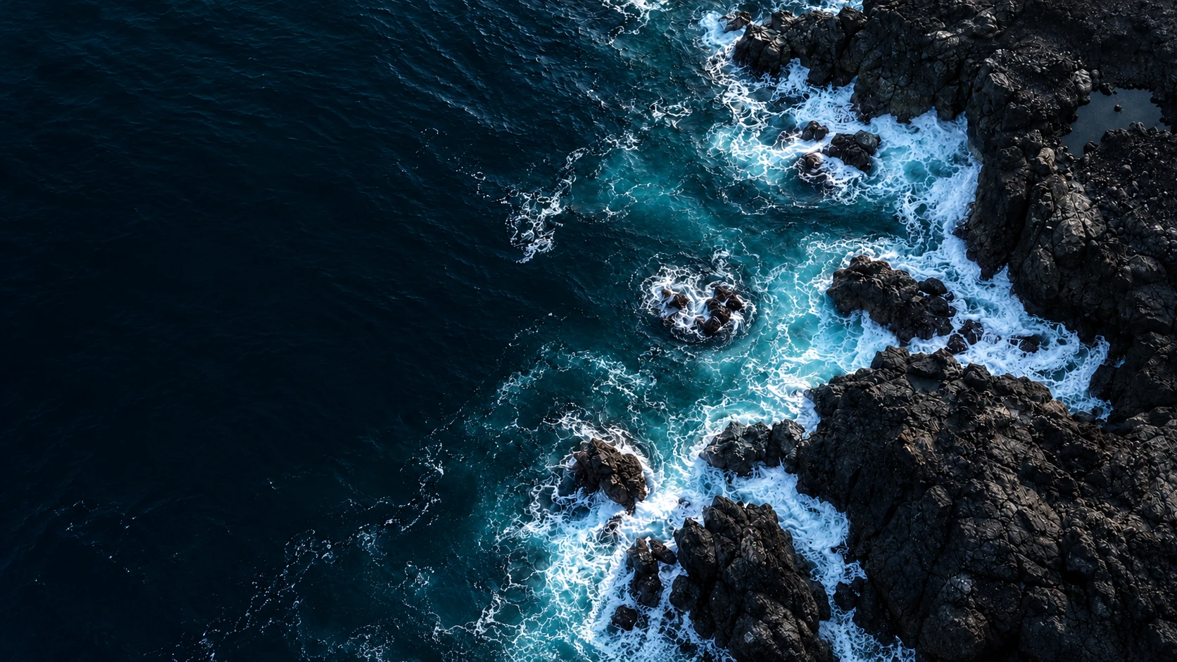 Dark blue ocean meeting a rocky coastline